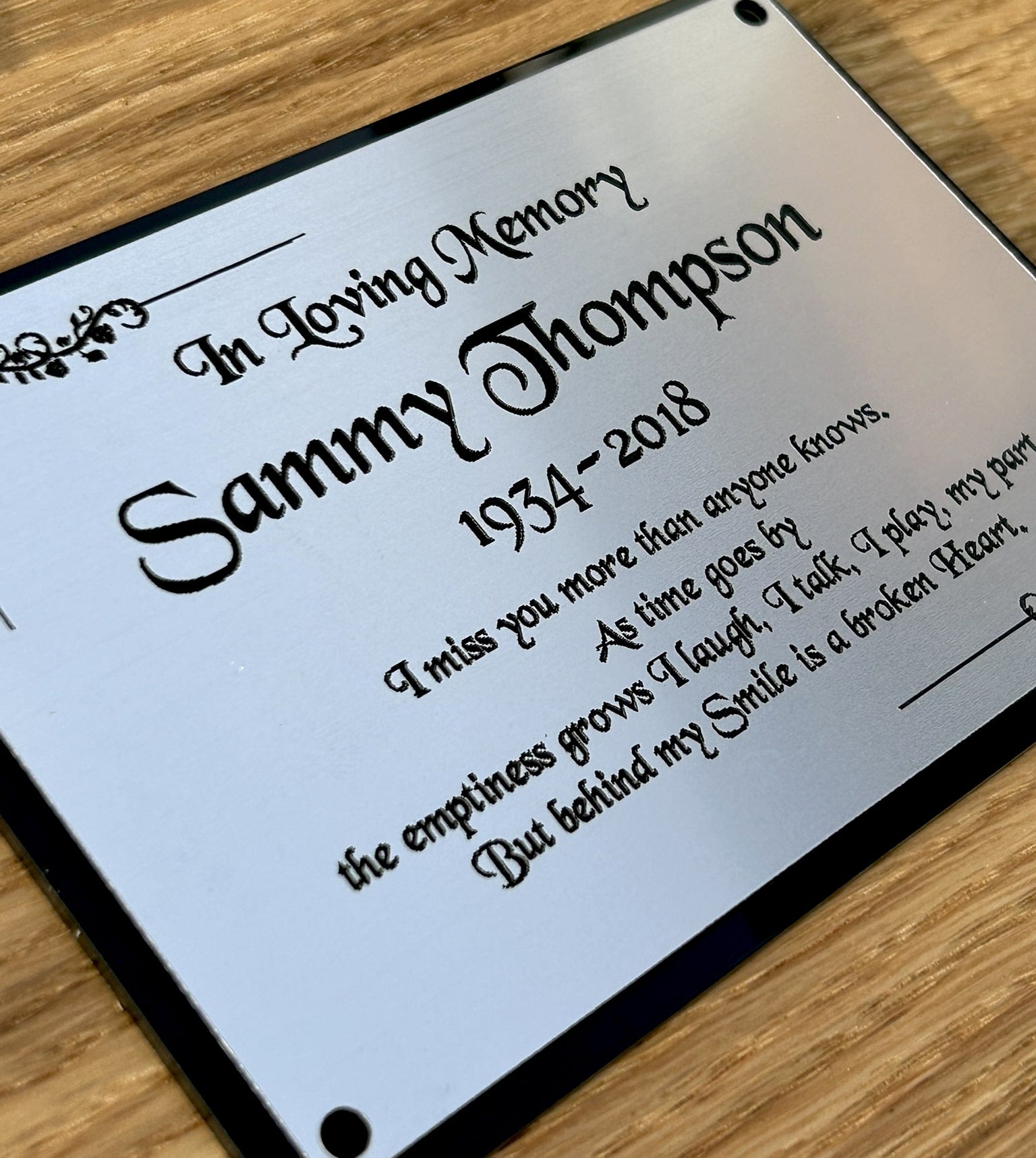 A personalized memorial bench plaque with silver and black colours, and square edges
