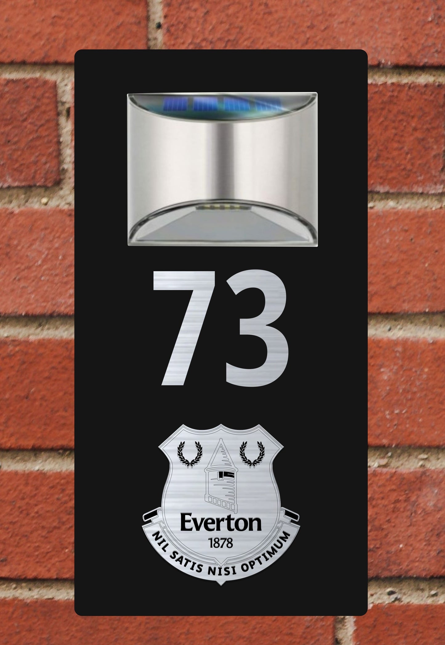 Solar light with number '73' and Everton logo on a brick wall