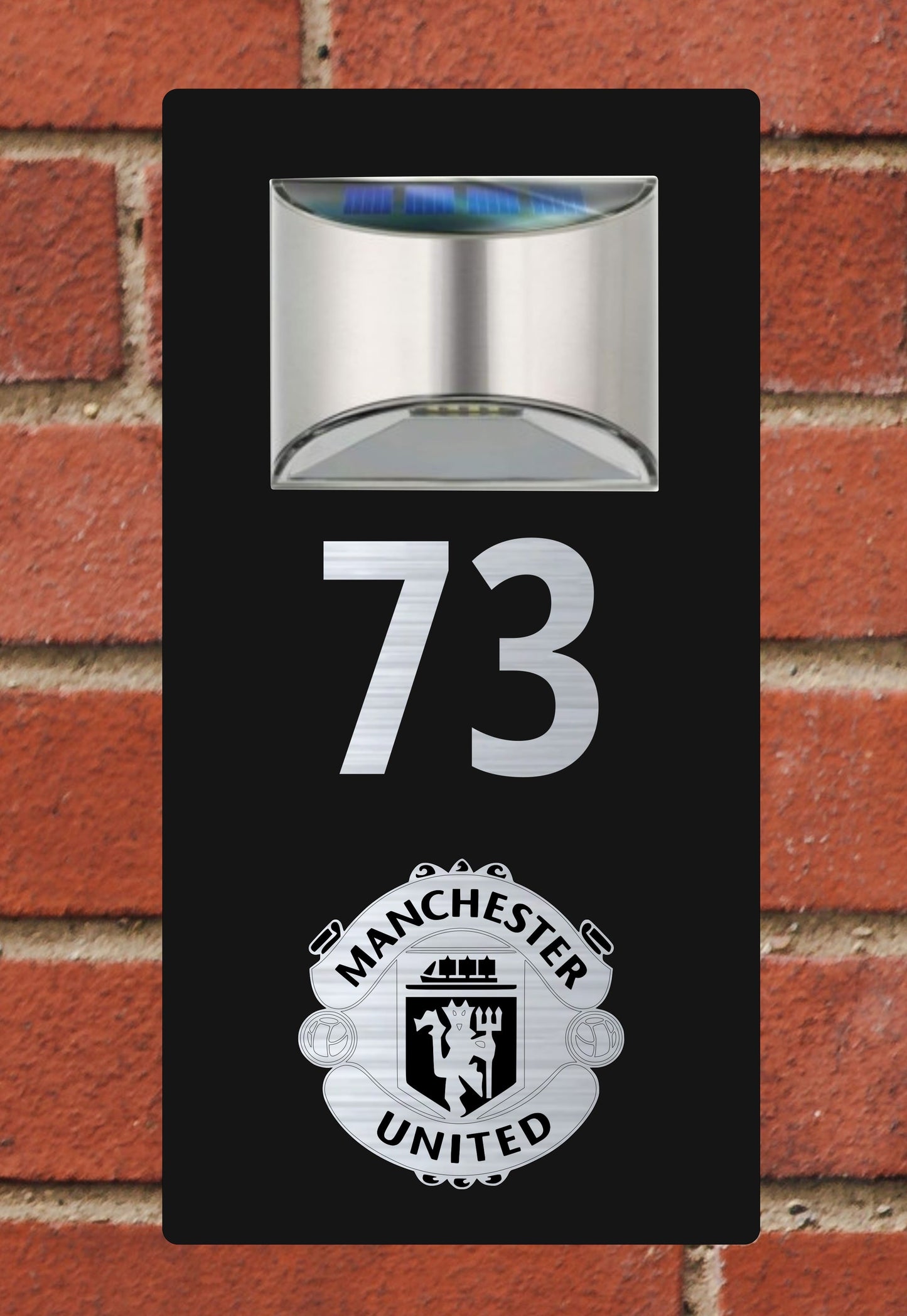 Manchester United house number sign with solar light on a brick wall