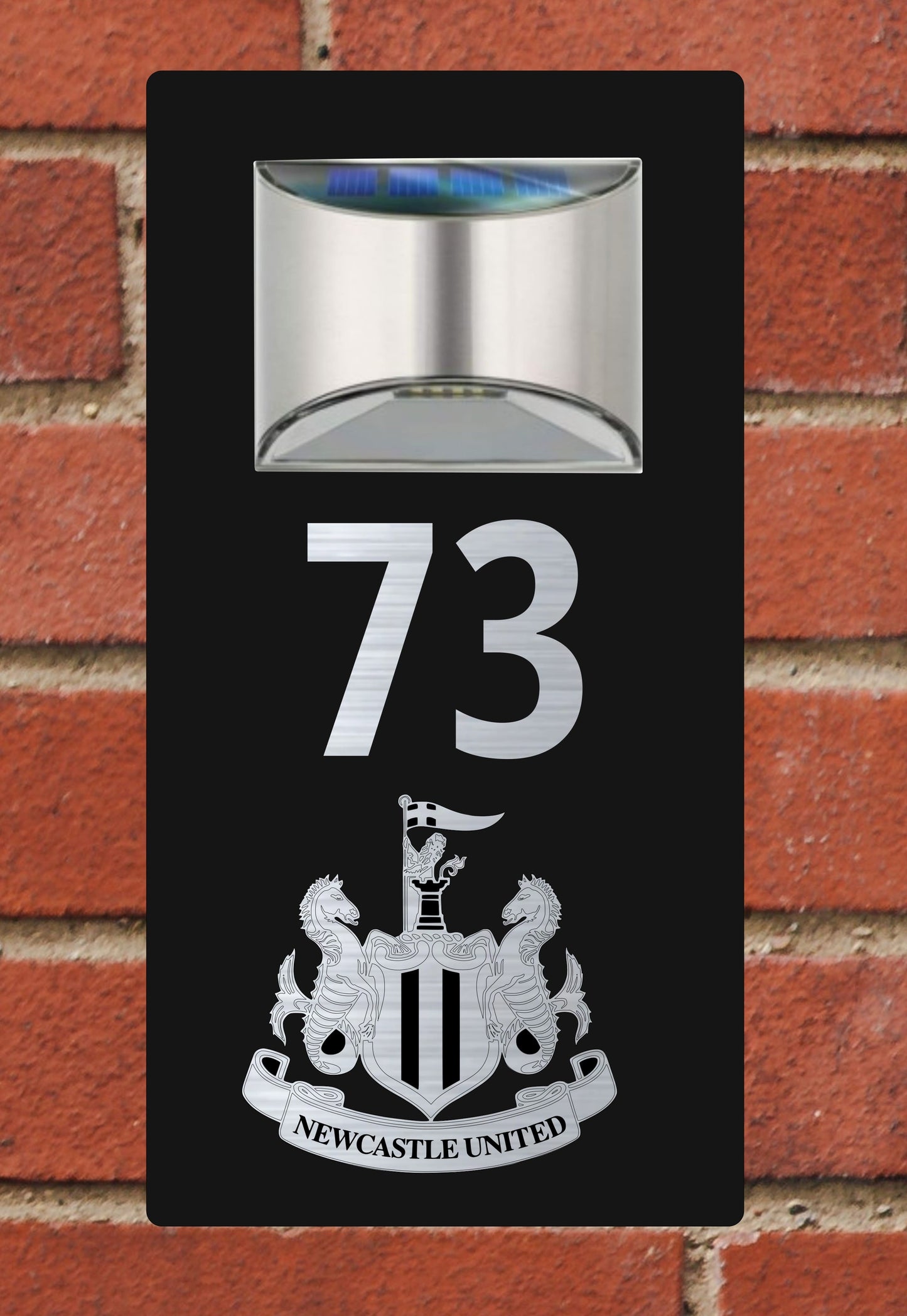 Solar light with number 73 and Newcastle United logo on a brick wall background
