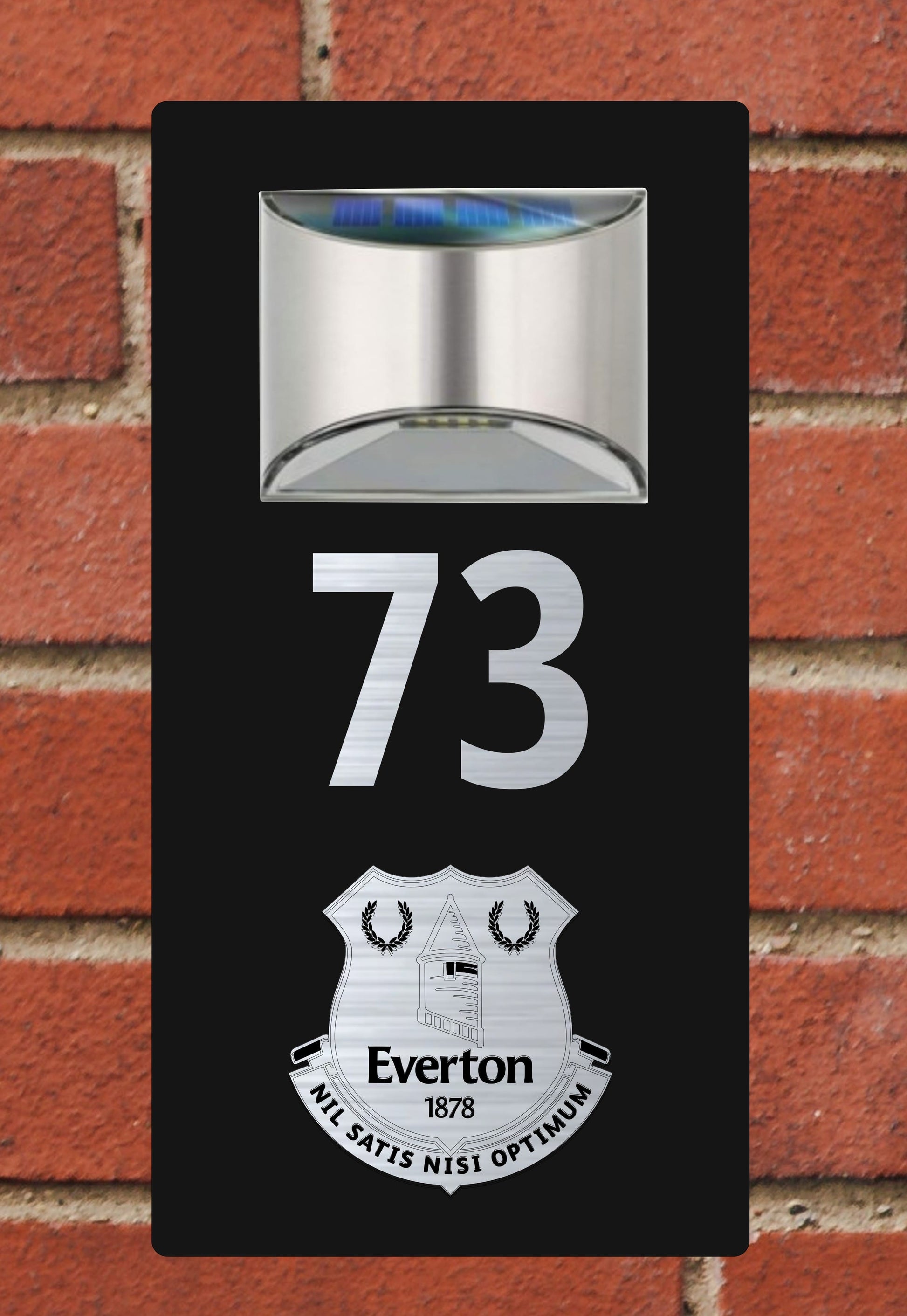 Solar light with number '73' and Everton logo on a brick wall